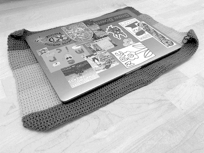 a photo of a laptop resting on a crocheted mat.